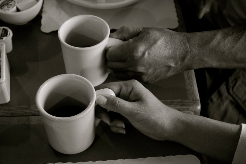 two hands each holding a coffee cup